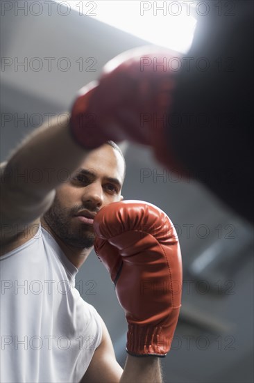 Close up of Hispanic man punching bag in gym