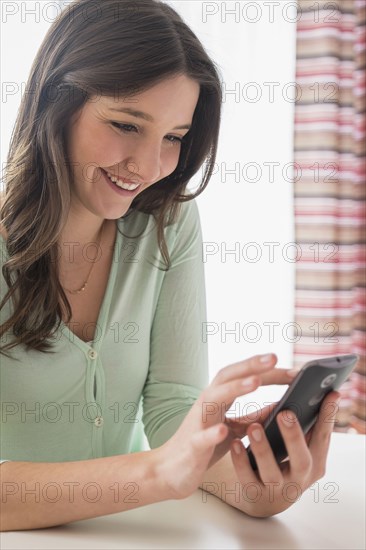 Smiling Caucasian woman texting on cell phone