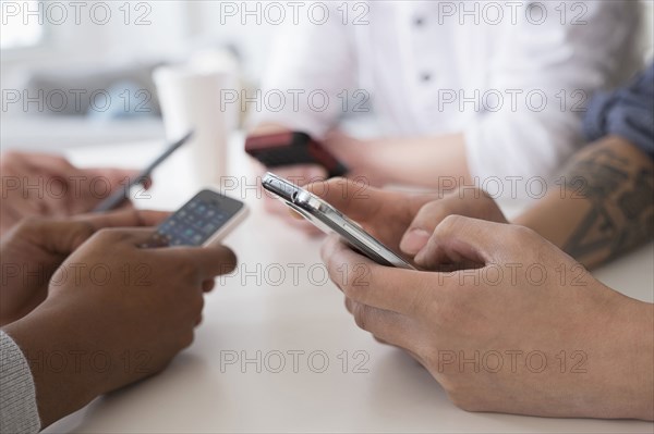 Close up of friends texting with cell phones at table