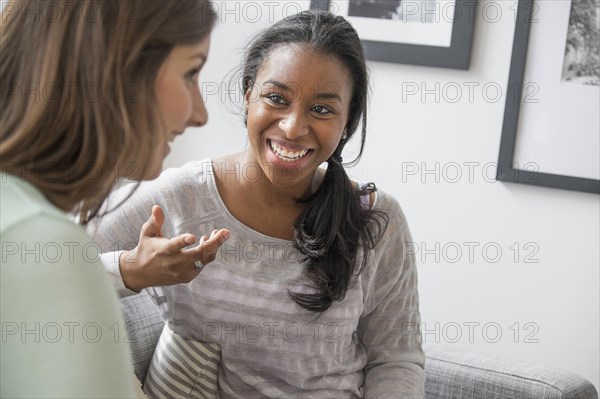 Smiling women talking on sofa