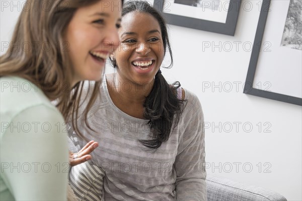 Smiling women talking on sofa