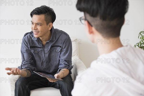 Men using digital tablet in living room