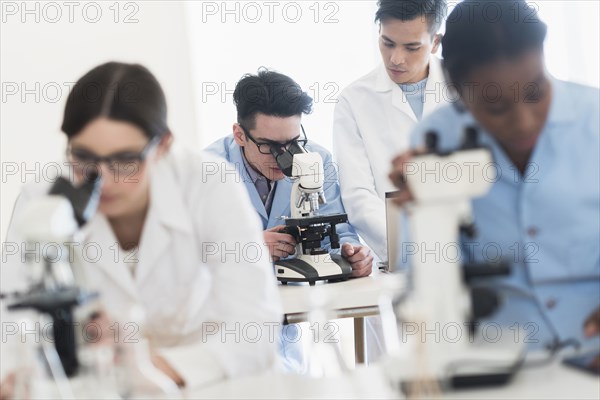 Scientists using microscopes in research laboratory