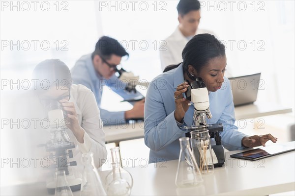 Scientists using microscopes and digital tablet in research laboratory