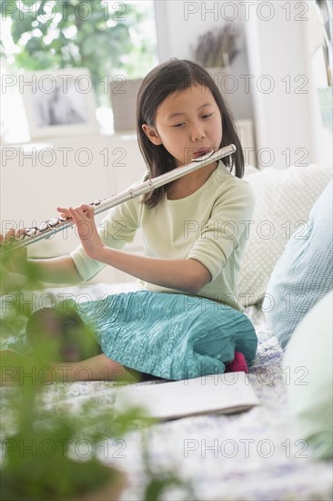 Chinese girl practicing flute on bed