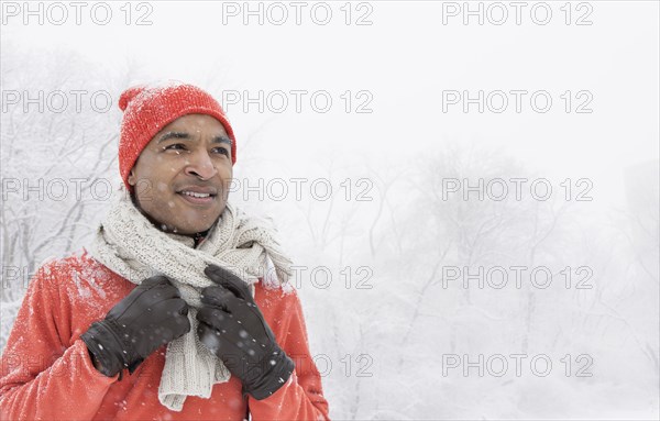 Black man wearing gloves and scarf in snow