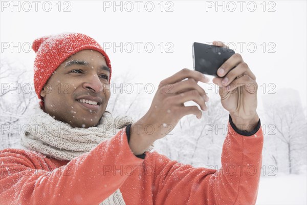 Black man using cell phone in snow