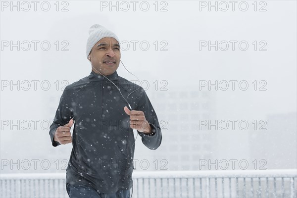 Black runner jogging in snow