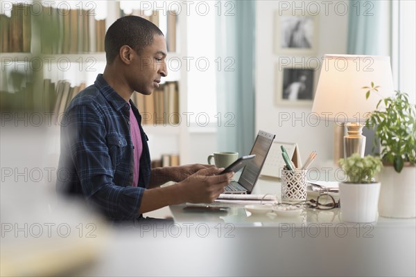 Black businessman using cell phone at desk