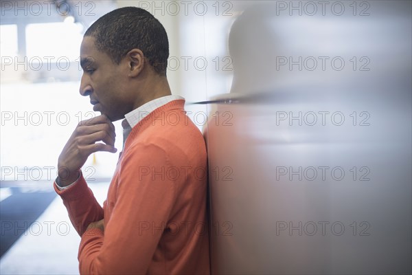 Black businessman leaning on wall