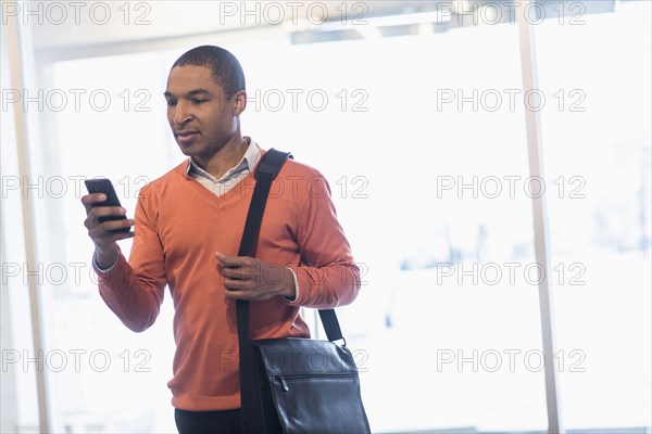 Black businessman with cell phone and messenger bag