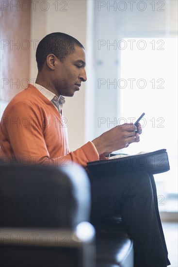 Black businessman using cell phone in office lobby