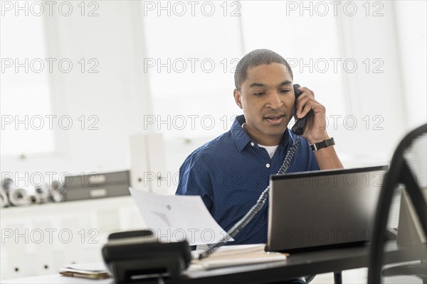 Black businessman talking on telephone in office