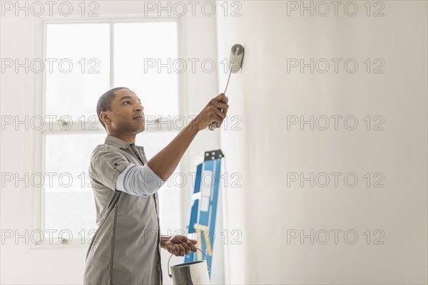 Black man painting wall of home