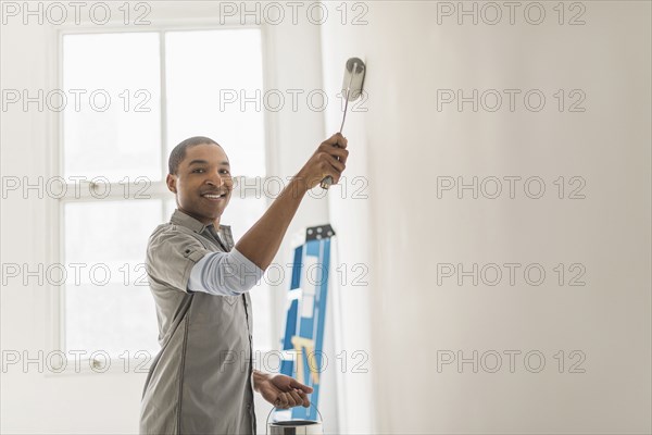 Black man painting wall of home