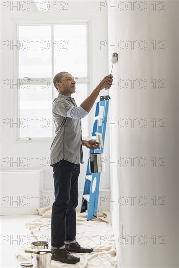 Black man painting wall of home