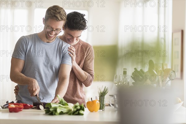 Caucasian gay couple cooking in kitchen