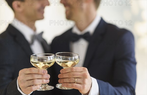 Caucasian gay grooms toasting with champagne at wedding