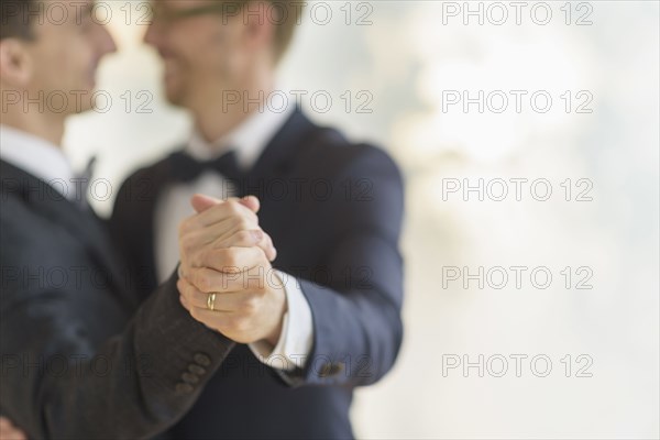 Caucasian gay grooms dancing at wedding