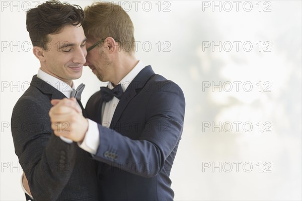 Caucasian gay grooms dancing at wedding