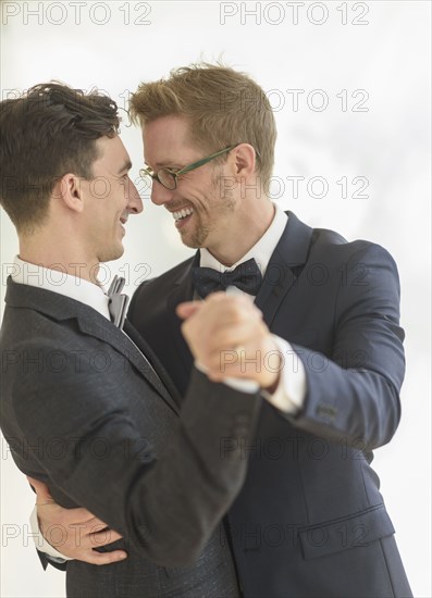 Caucasian gay grooms dancing at wedding