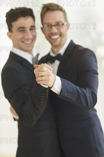 Caucasian gay grooms dancing at wedding