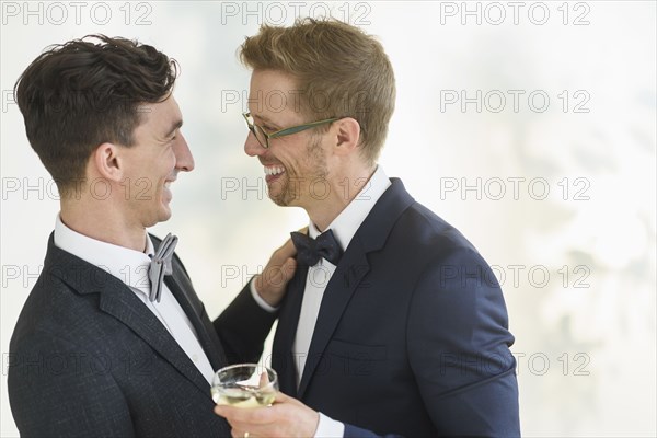 Caucasian gay grooms hugging at wedding