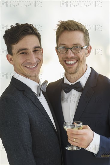 Caucasian gay grooms drinking champagne at wedding