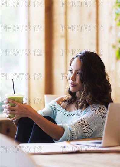 Chinese woman drinking smoothie in cafe