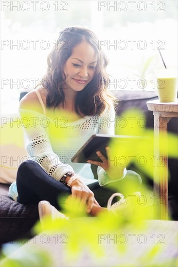 Chinese woman using digital tablet on sofa