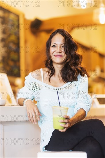 Chinese woman drinking smoothie in cafe
