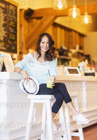 Chinese woman drinking smoothie in cafe