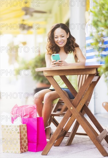 Chinese woman using cell phone at sidewalk cafe