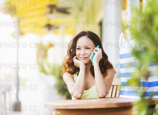 Chinese woman talking on cell phone at sidewalk cafe