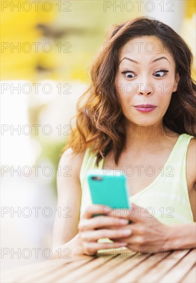 Chinese woman using cell phone at sidewalk cafe