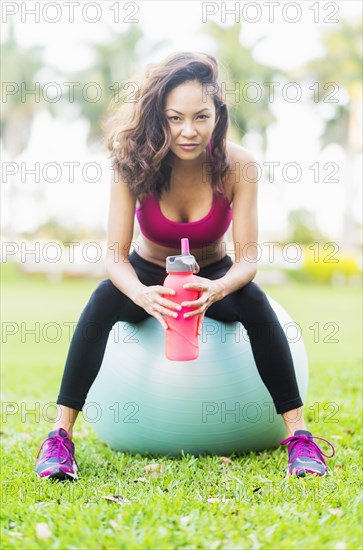 Chinese woman sitting on fitness ball in park