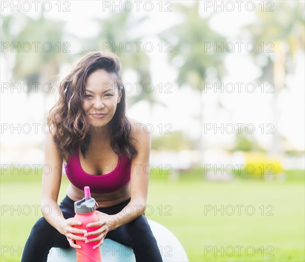 Chinese woman sitting on fitness ball in park