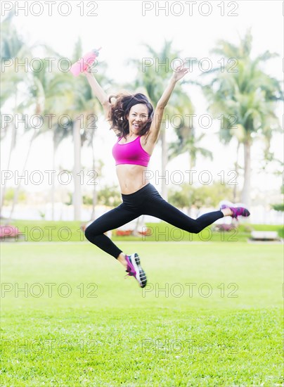 Chinese woman jumping for joy in park