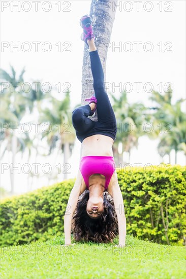 Chinese woman doing handstand against tree in park