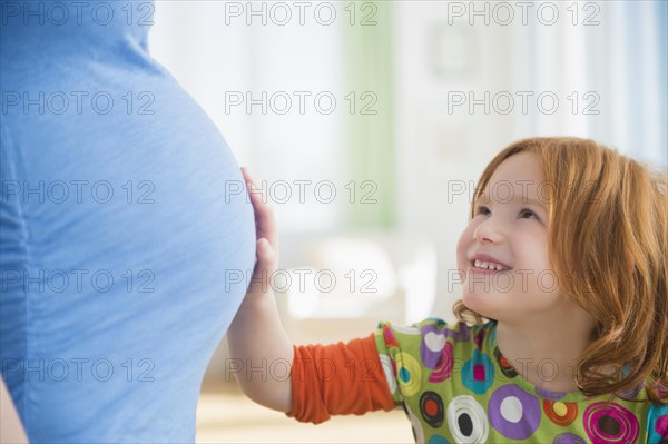 Caucasian girl touching belly of pregnant mother