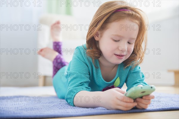 Caucasian girl using cell phone on floor