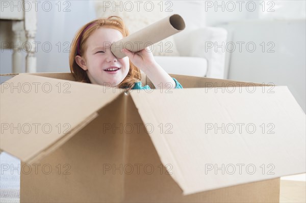 Caucasian girl playing in cardboard box