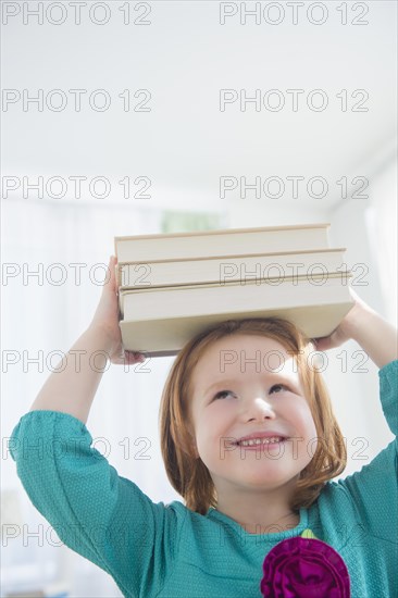 Caucasian girl balancing books on head