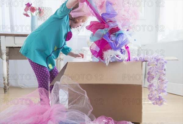 Caucasian girl unpacking dress-up clothes from box