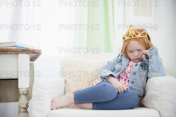 Upset Caucasian girl pouting in armchair