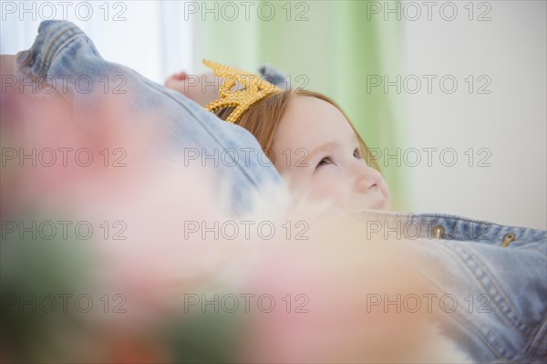 Caucasian girl wearing tiara on sofa
