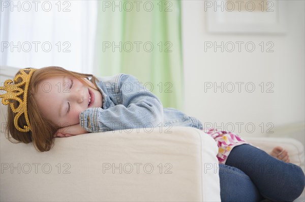 Caucasian girl wearing tiara in armchair