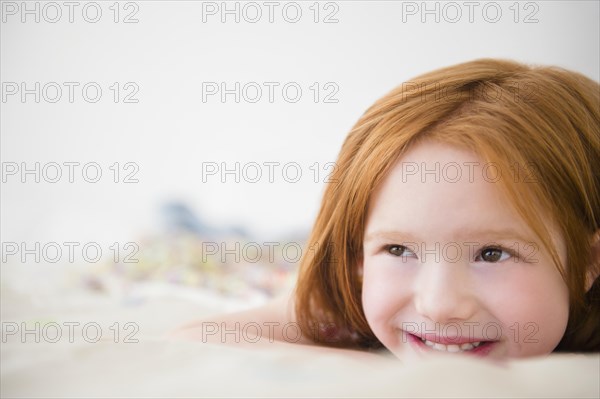 Smiling Caucasian girl laying on bed