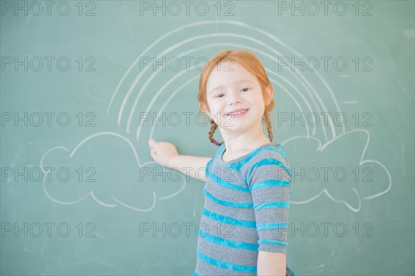 Caucasian girl drawing on chalkboard