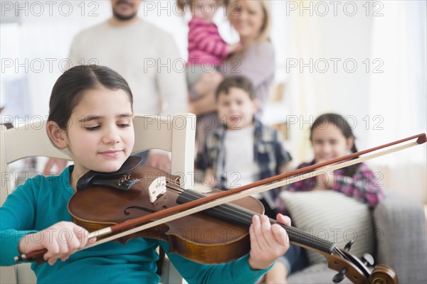 Caucasian girl playing violin in living room
